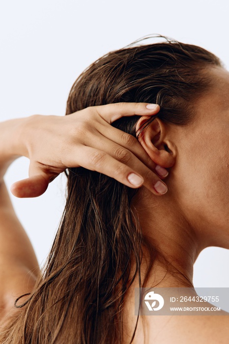 A woman with long hair stands back and takes care of her hair after washing and applying scalp and hair health products. Taking care of your hair at home