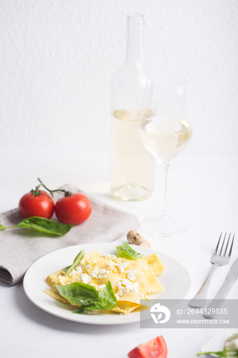 Boiled ravioli with basil, cheese and tomatoes on white table