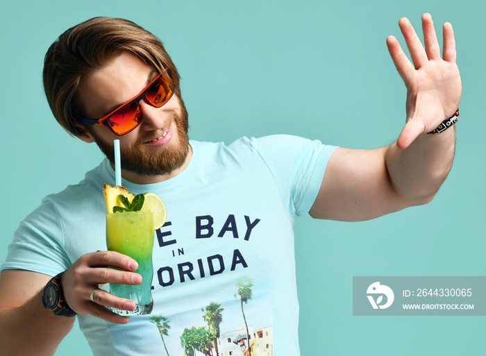 Young man hold blue hawaiian margarita cocktail drink juice happy smiling pointing one finger