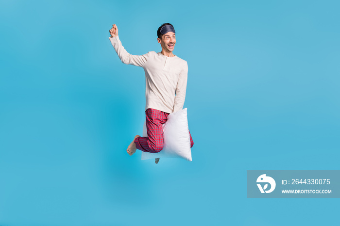 Photo portrait full body view of man flying riding pillow like magic broom jumping up isolated on vivid blue colored background