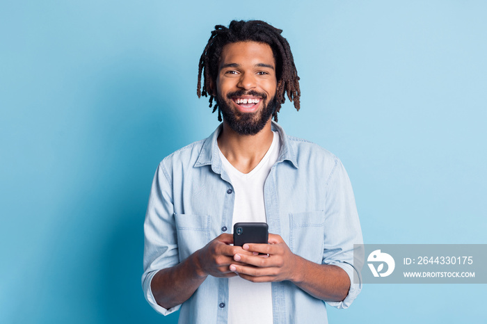 Portrait of attractive glad cheerful guy using device browse media free time isolated over bright blue color background