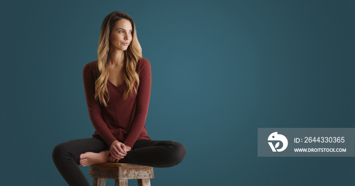 Female millennial looking off camera and smiling on blue background