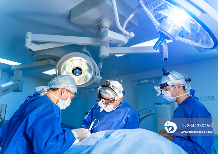 Spinal surgery. Group of surgeons in operating room with surgery equipment. Doctor looking at screen. Modern medical background