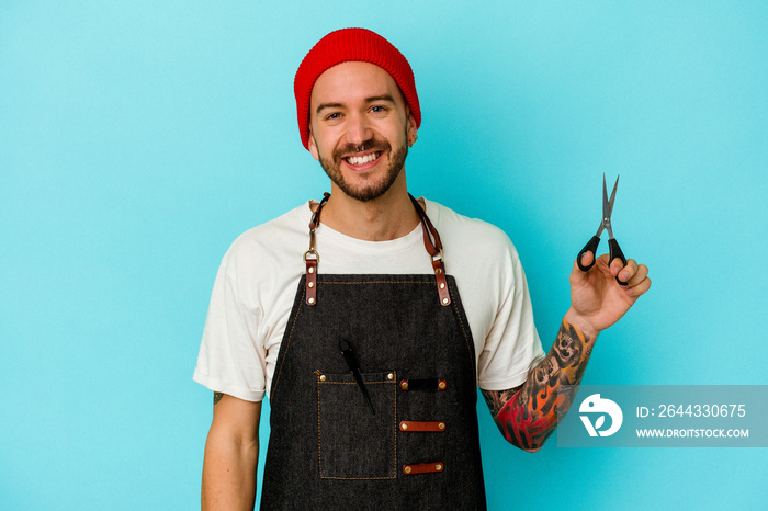 Young tattooed barber man isolated on blue background happy, smiling and cheerful.