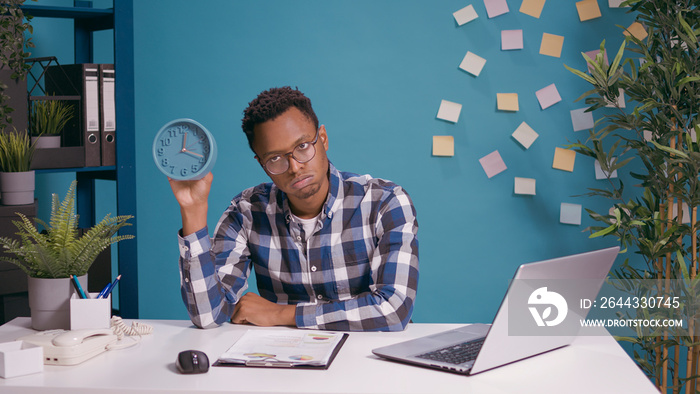 Impatient man waiting to finish work and checking time on clock, feeling tired and displeased. Serious upset person looking at watch to see deadline delay and time before break.