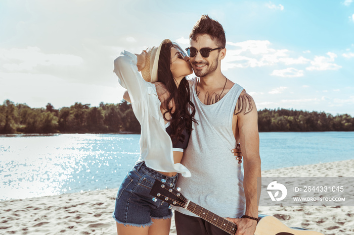 woman kissing man while walking together on beach on summer day