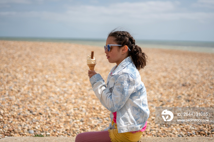 Girl (8-9) eating ice cream on beach