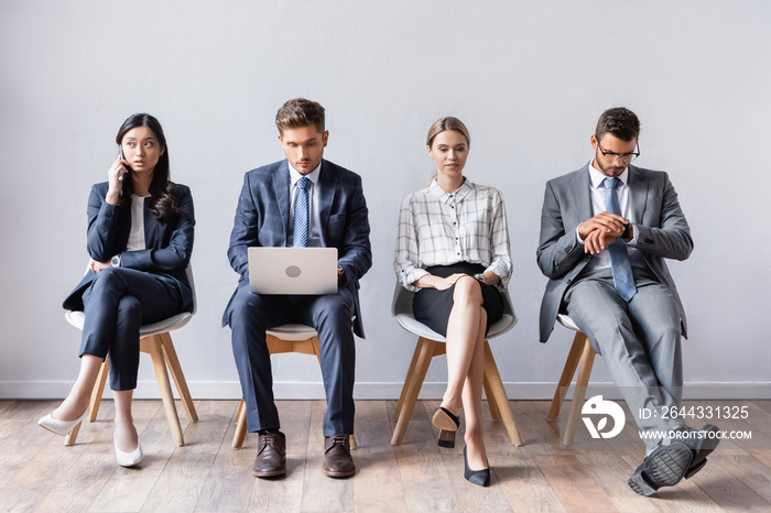 Multiethnic business people with laptop and smartphone waiting in hall