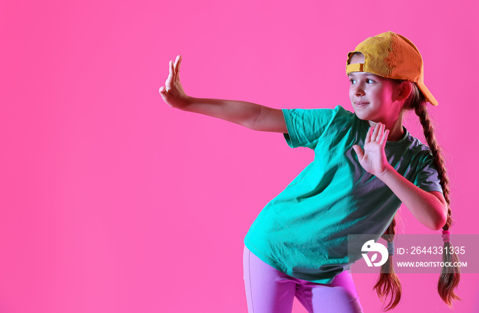 Cute little girl in cap dancing on pink background