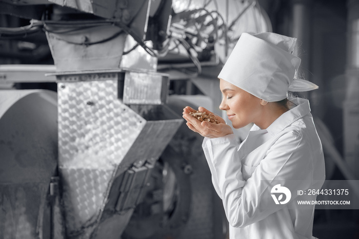 Wheat bran production factory mill, woman worker holds finished product in hands