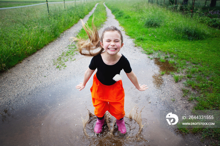 little girl jump in puddle on an summer walk