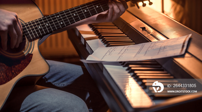 man playing acoustic guitar and piano close-up, recording notes