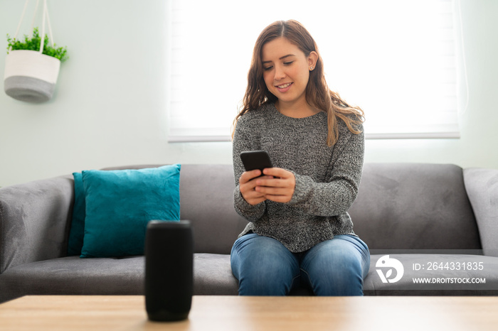 Pretty woman conecting her cellphone to her smart speaker