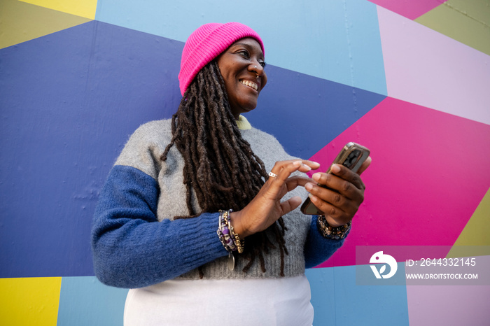 Beautiful woman using phone on colorful background