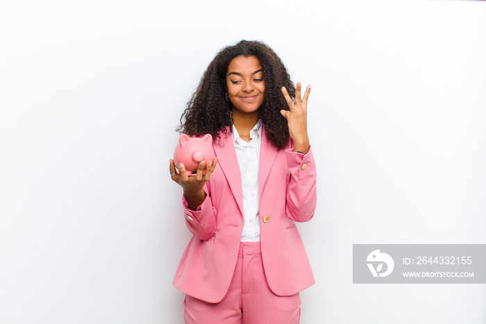 young pretty black woman with a piggy bank against white wall