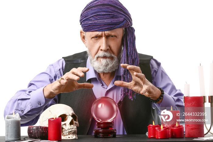 Male fortune teller with crystal ball at table on white background