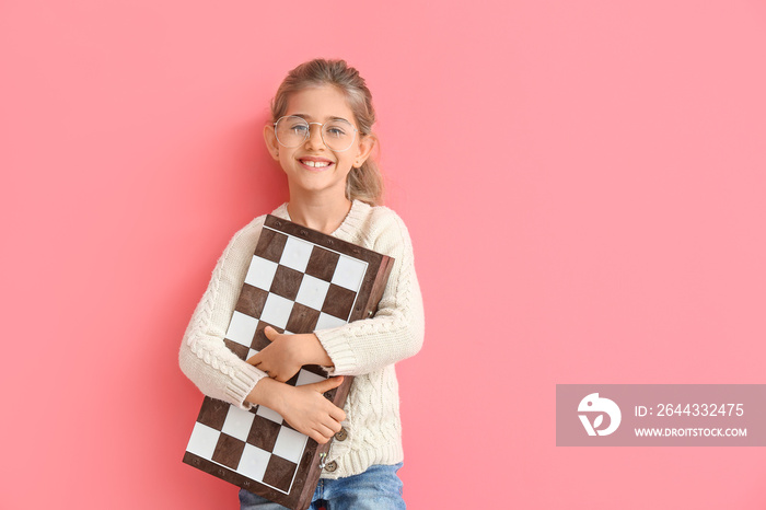 Cute little girl with chessboard on color background