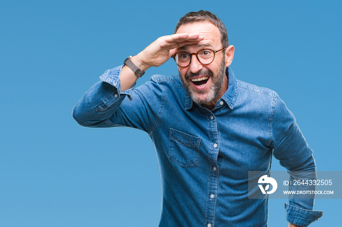 Middle age hoary senior man wearing glasses over isolated background very happy and smiling looking far away with hand over head. Searching concept.