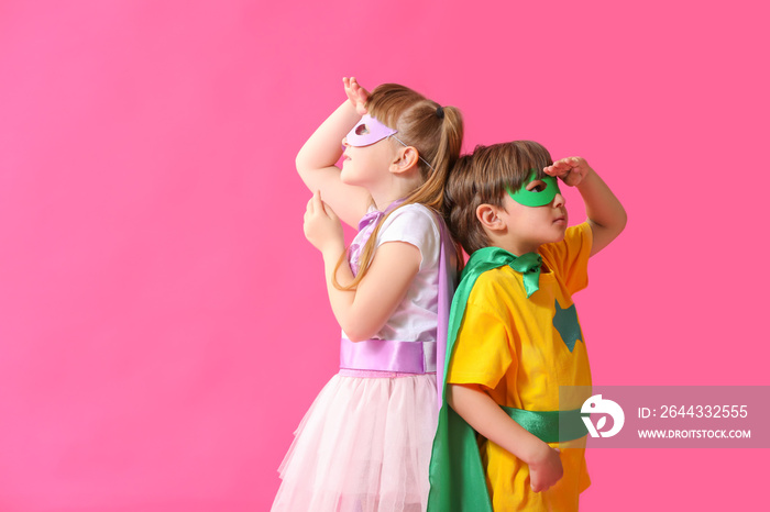 Cute little children dressed as superheroes on color background