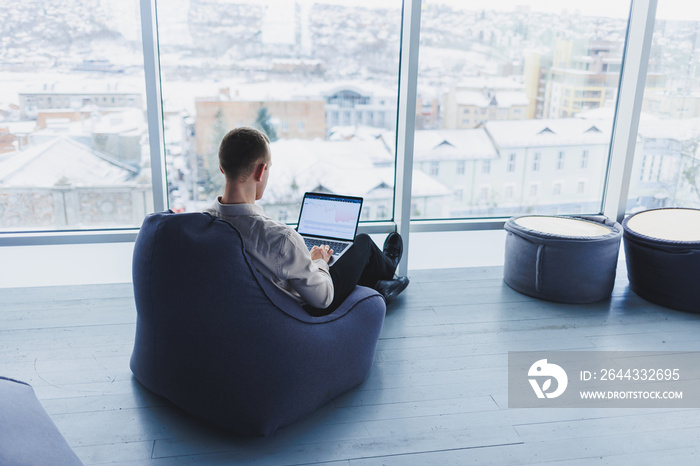 Young smart male businessman is sitting in the office and working on a project related to public cyber technology. Businessmen with laptop trying to meet deadlines in external marketing.