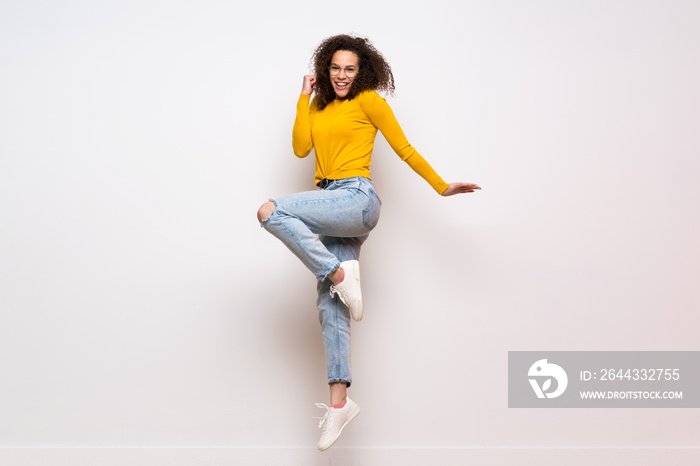 Dominican woman with curly hair jumping over isolated white background