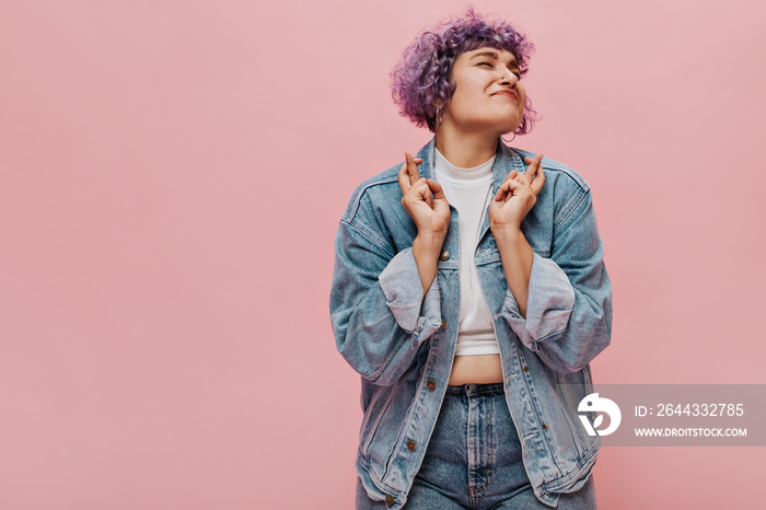 Curly charming woman in good mood and in bright clothes smiling. Cute adult girl in short top rejoices at something on pink background..