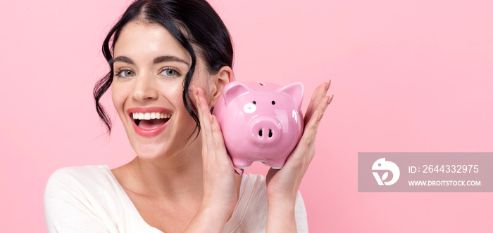 Young woman with a piggy bank on a pink background