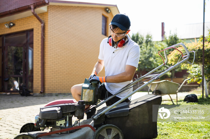 Man with a canister of gasoline in his hands refueling a lawn mower