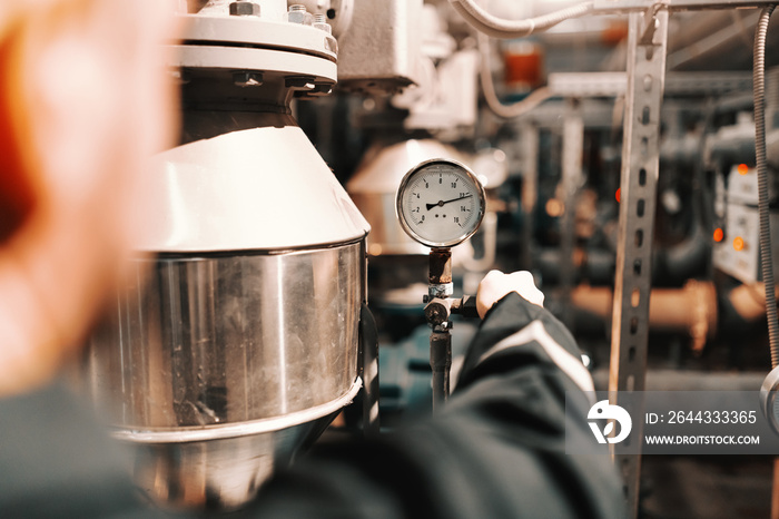 Close up of worker in heavy industry plant adjusting air pressure on boiler.