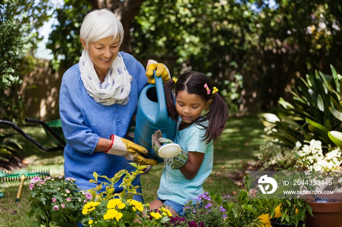 Smiling grandmother and granddaughter watering plants