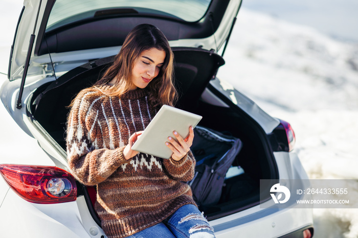 Young traveler woman using digital computer in snowy mountains in winter.