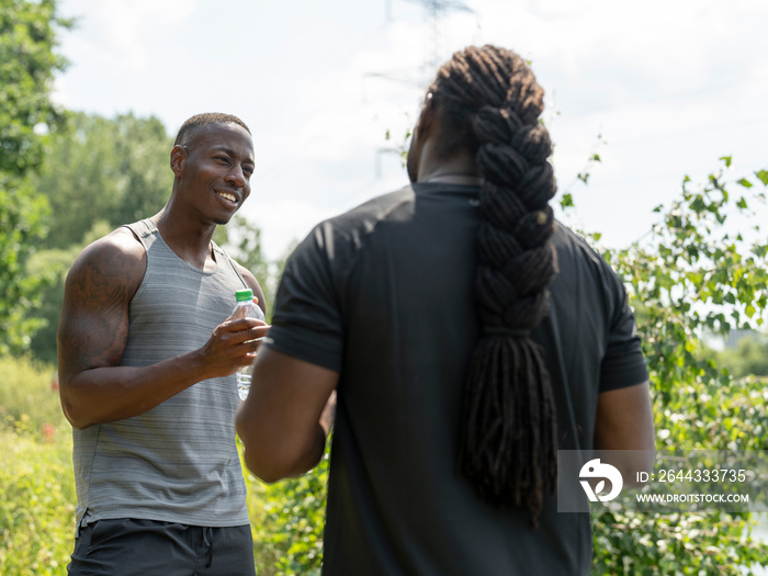 Two men drinking water after exercising outdoors