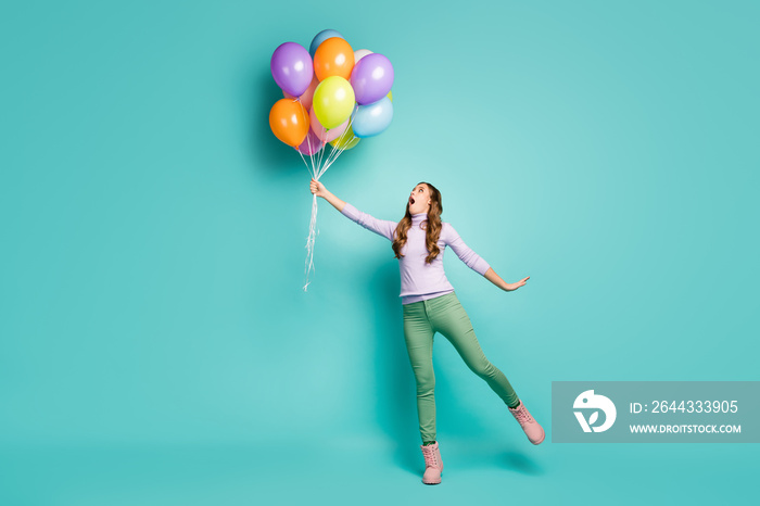 Full length profile photo of pretty crazy lady hold many colorful air balloons fly away with wind blowing wear lilac jumper green pants shoes isolated teal pastel color background