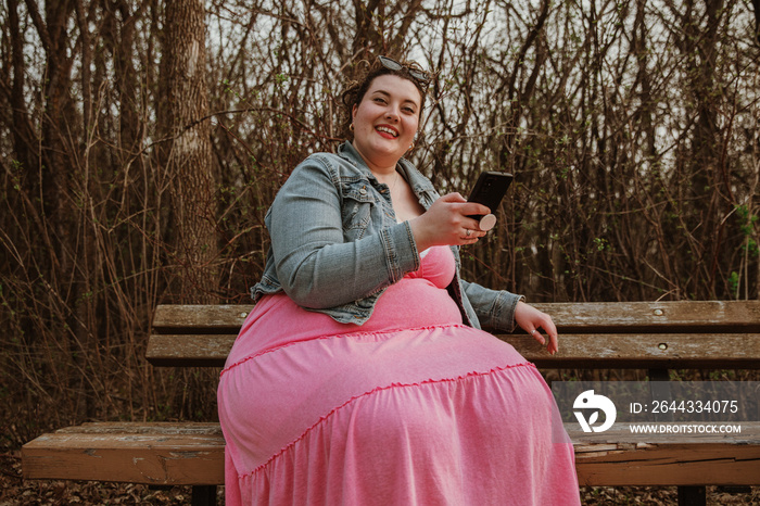 woman sits on bench holding phone