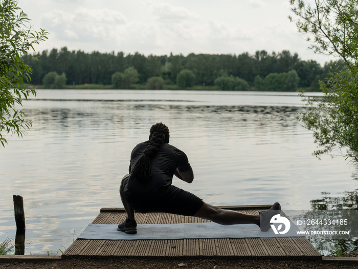 Man practicing yoga by lake