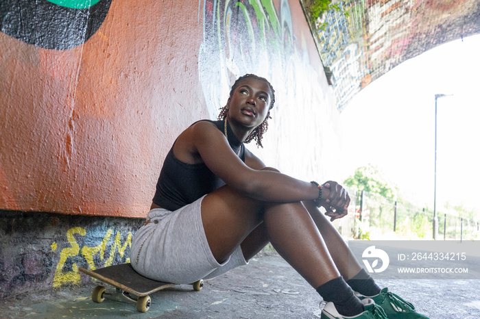 Young woman sitting on skateboard