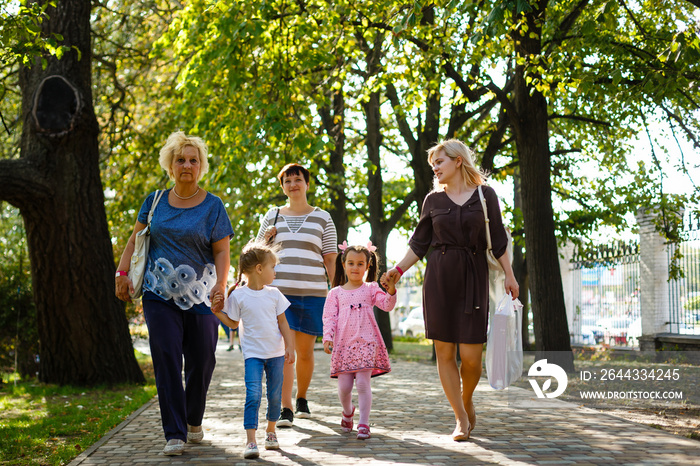 Big happy family on a walk in the park. Grandmother, daughter and granddaughter walk in the spring. Women of all ages have fun together