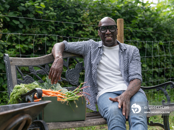 Smiling mature man resting on bench after working in garden