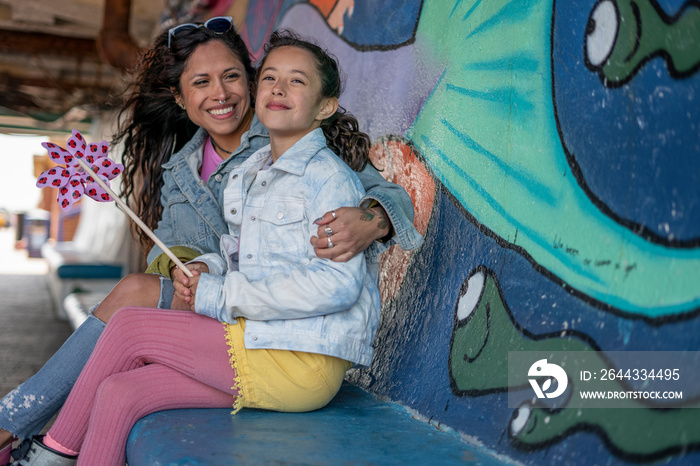 Smiling mother and daughter (8-9) sitting in tunnel with graffiti