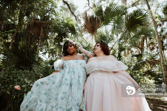 2 plus size woman standing together wearing dresses in the forest