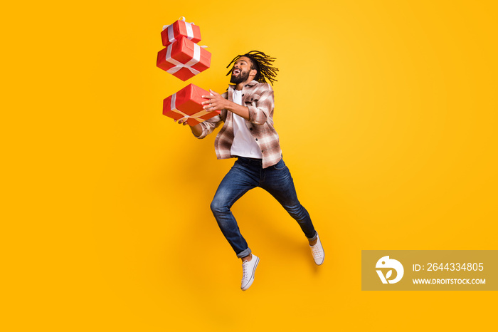 Full length body size view of nice cheerful guy jumping throw drop falling giftboxes isolated over bright yellow color background