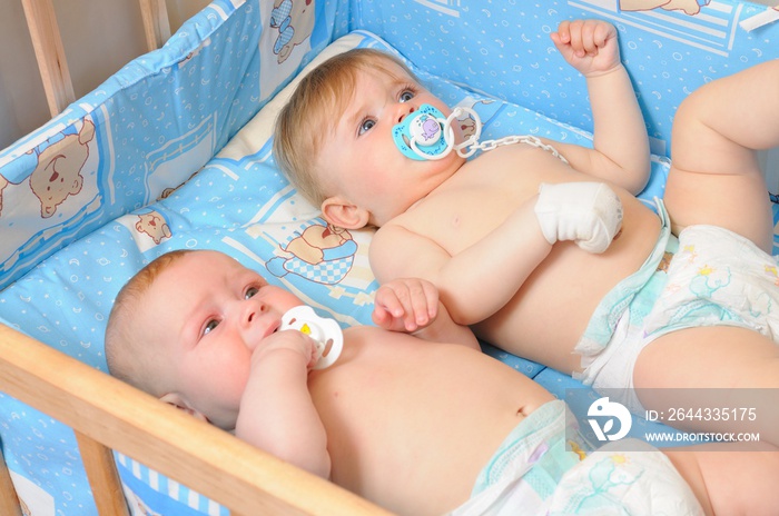 Two babies lying in wooden crib