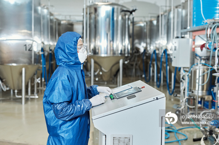 Worker in protective gear operating equipment at factory