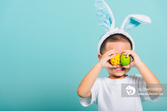 child boy wearing bunny ears and white T-shirt, standing to holds easter eggs instead of eyes