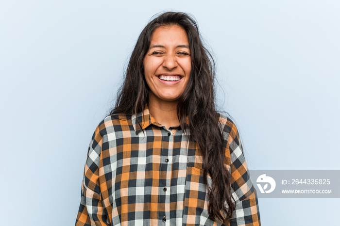 Young cool indian woman laughs and closes eyes, feels relaxed and happy.