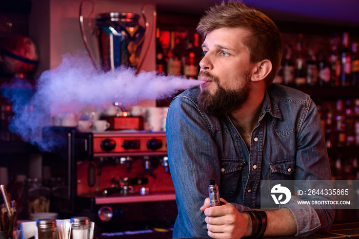 Vape. Vaping man in a cloud of vapor. Photo is taken in a vape bar.