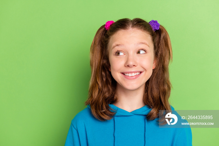 Photo of positive young happy little girl look empty space good mood smile isolated on green color background