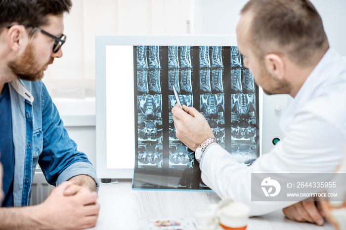 Man during the medical consultation with senior therapist looking on the tomography print at the office