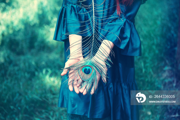 Peacock feather in woman’s hand