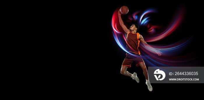 Flying. Beautiful african-american male basketball player in motion and action in neon light on black background. Concept of healthy lifestyle, professional sport, hobby.